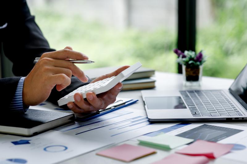 Man working with calculator in hand and laptop in front of him