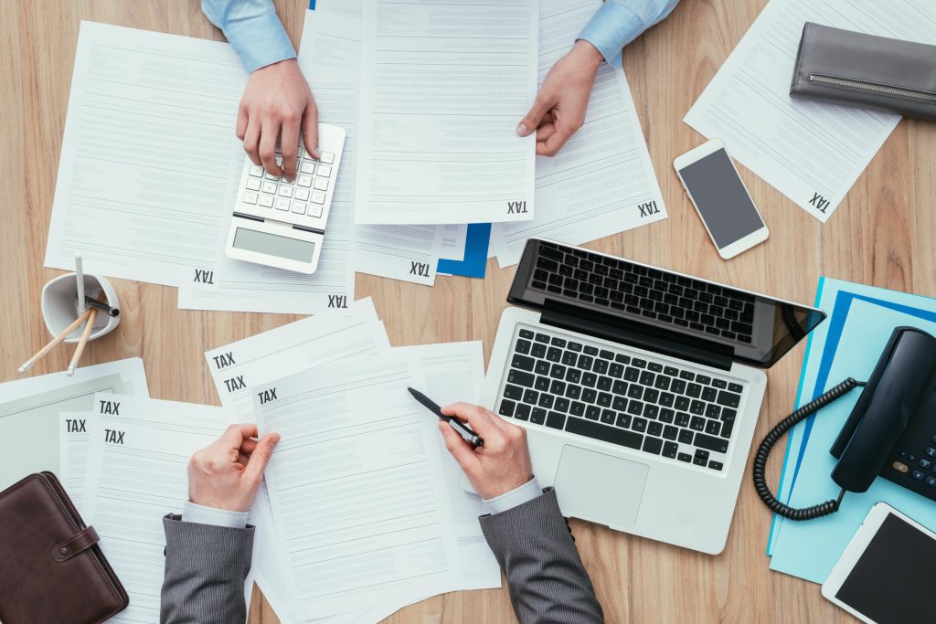 People working around the table with paperwork and a laptop