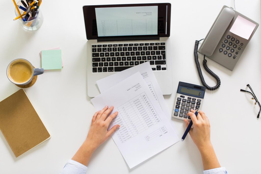 Person working on laptop and with paperwork